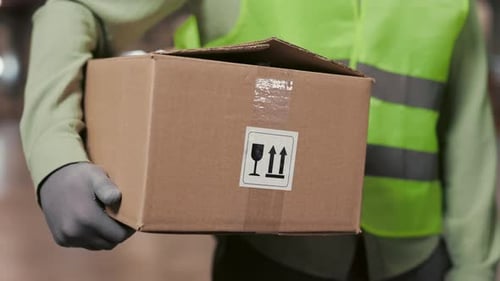Male Worker Standing in Retail Warehouse Holding Cardboard Box Working in a Logistics and