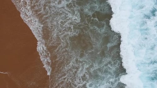Blue waves break on a beautiful sandy beach. Sea waves on the beautiful beach aerial view drone.