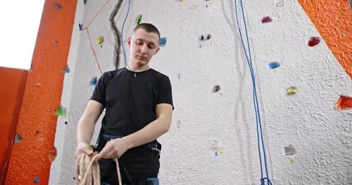 Man Prepares Climbing Rope at Indoor Rock Gym