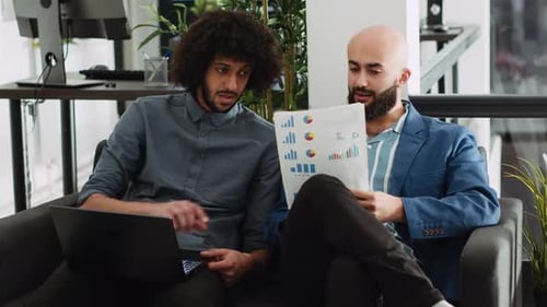 Two Business Men Reviewing Charts on Couch