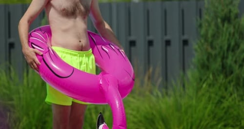 Man Holding Flamingo Pool Float Outdoors on Sunny Day