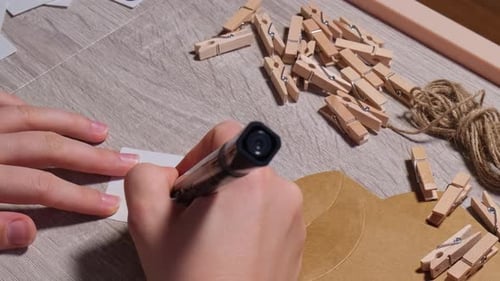 Unrecognizable Young Woman Sticks Number on Craft Bag Fastens with Clothespin Female Making Kraft