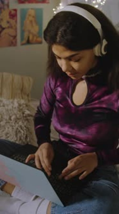 Girl in Headphones Sits on Bed in Her Room and Surfs Internet