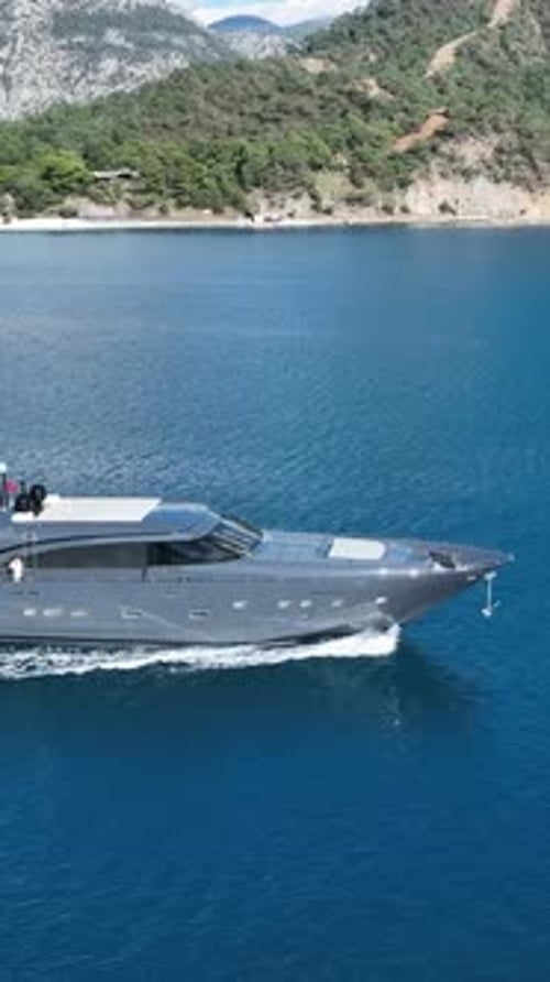 Aerial of a Luxury Yacht: A sleek yacht slices through the pristine blue ocean, leaving a trail of f
