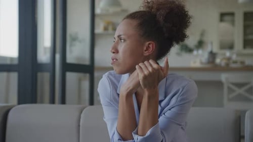 Woman With Headache Sits on Sofa in Home