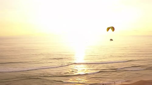 Sunset aerial drone tracking shot of paramotorers over a beach in Weligama, Sri Lanka.