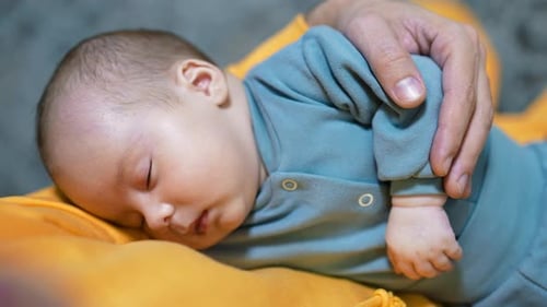 Beautiful small child sleeping tightly in father's arms. Cute baby boy in blue suit having sleep.