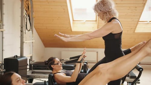 Women Doing Pilates Exercises in Bright Studio