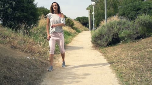 Young runners exercising in green park with tired woman taking a break