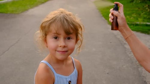 Little Girl Gets Bug Spray Applied on a Path
