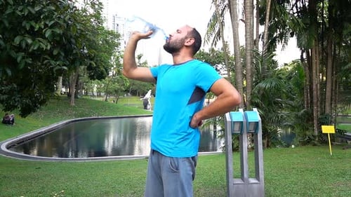 Happy Male Jogger Drinking Water After Workout in City Park, Super Slow