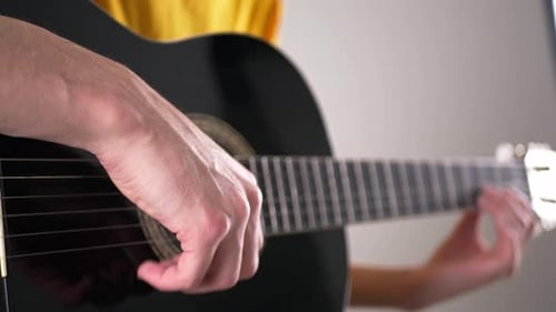 Hands Strumming a Black Acoustic Guitar Close Up