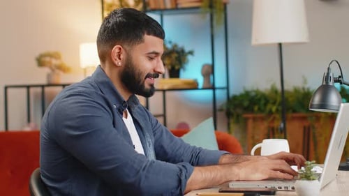 Smiling Indian Man Freelancer Typing Working on Laptop Writing Important Email From Home Office