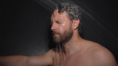 Man Taking Shower in Dark Modern Bathroom