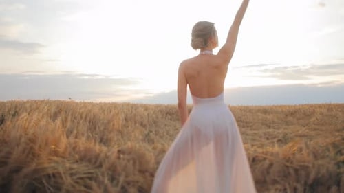 Woman Dancing Amidst Vast Field with Warm Glow of Rising Sun