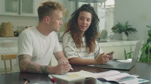 Young Couple Paying Bills Together at Kitchen Table