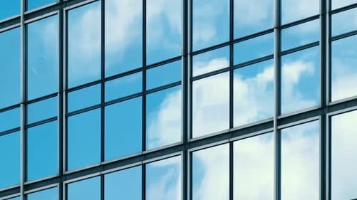 Time lapse of blue sky and clouds reflected in structural modular glass wall.