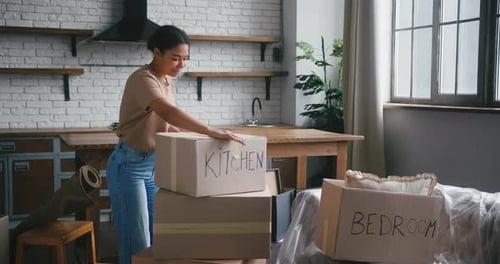 Woman Taping Boxes in New Apartment