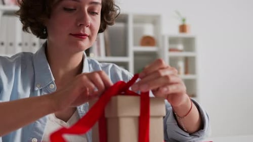 Woman Opens Birthday Gift Box With Red Ribbon