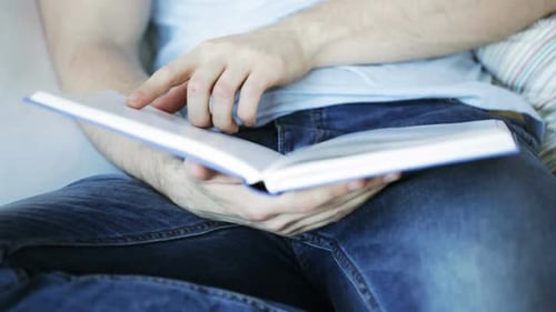 Close Up of Man Sitting on Couch and Reading Book at Home Activity