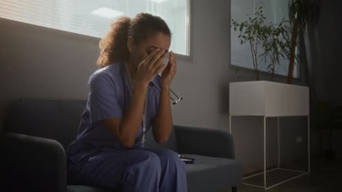 Stressed Health Professional Reads Clipboard in Hospital