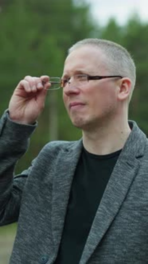 Man Removes Glasses in Nature Portrait