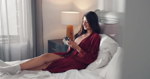Woman Relaxing in Bed Using Her Phone