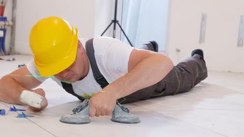 Man installs floor tile with laser level