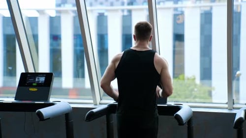 Athletic Man Uses Treadmill in Bright Gym