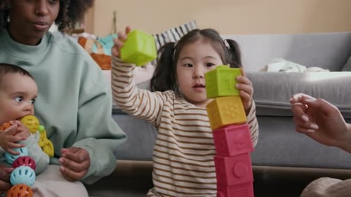 Mulheres e garotinha construindo torre enquanto brincam com o construtor