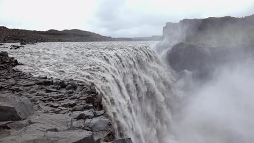 Handheld shot of a mighty big waterfall with a large fall of the water, flowing very fast through
