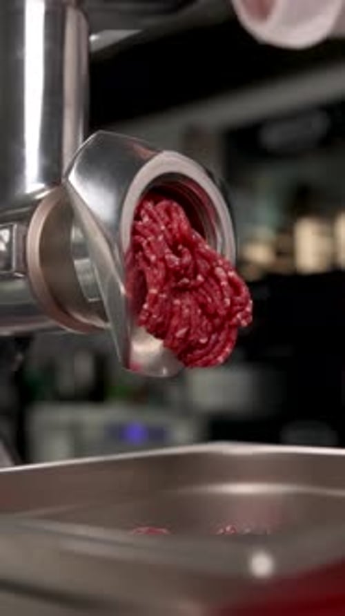 the chef cuts meat on a meat grinder