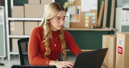 Woman Working on Laptop with Shipping Boxes
