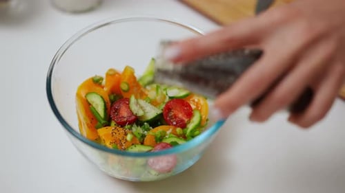 Closeup Female Hand Spicing Organic Salad with Pepper Seasoning in Slow Motion Closeup Young