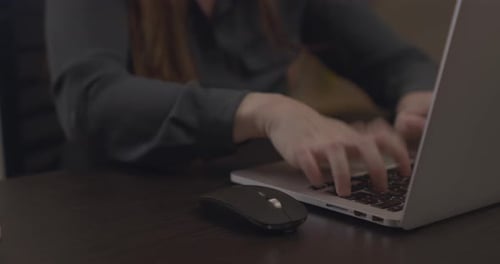 Woman Typing on Laptop Keyboard at Dark Desk