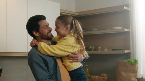 Happy Father Holding Daughter in Modern Kitchen