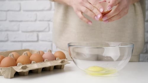 Woman Cracking Eggs into Glass Bowl for Cooking