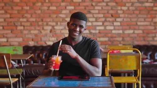 youth, technology - young black man at pub with tablet toasts to the camera
