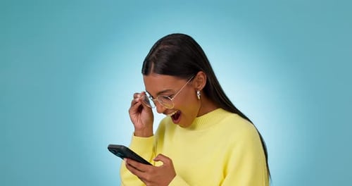 Phone winner, wow or happy woman with notification of good news in studio isolated on blue