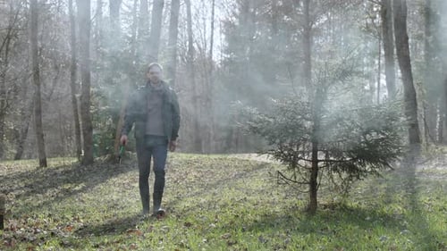 White Serious Man in Jacket with Ax Walks Out of Forest Through Smoke