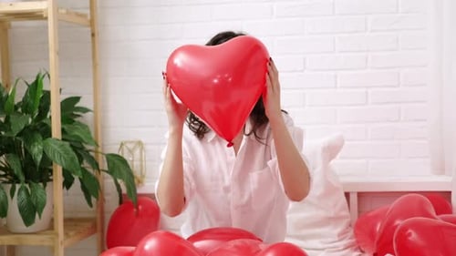 Red Heart Shaped Balloon Close Up in Hands of Brunette Smiling Girl on Valentines Day
