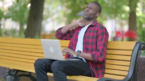Man Using Laptop on Bench Has Neck Pain