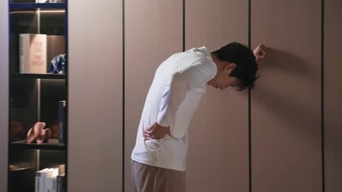 Tired young man experiencing discomfort in lower back pain, cervical spondylosis, muscle weakness. H