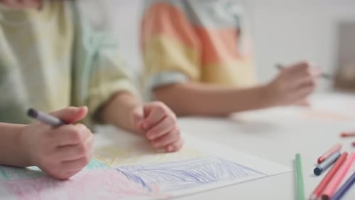 Children Drawing with Crayons Together at a Table