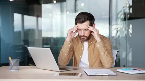 Businessman has depression suffering from mental pain while sitting at workplace in business office.