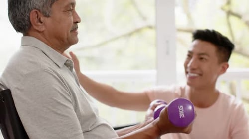 Senior Man Exercising with Weights, Assisted by Adult Man