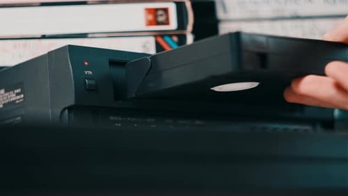 Male Hand Inserts VHS Cassette Into a VCR Video Player