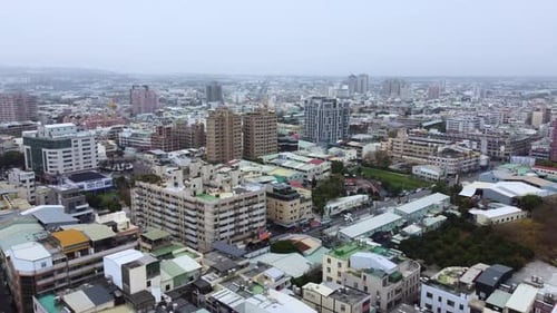 A dense cityscape on an overcast day, showcasing buildings and streets, aerial view