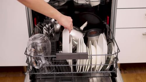 Loading Dishes into a Modern Stainless Steel Dishwasher