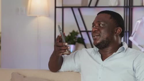 Man Holding Cell Phone While Sitting on Couch